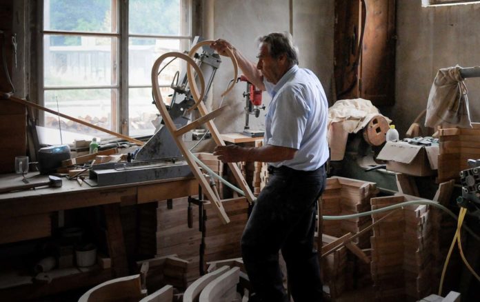 Holz statt Plastik: Rodel-Schlitten aus dem Bregenzerwald überdauern Generationen Edmund Johler steht an einer der Werkbänke unter den Fenstern der Rodel-Manufaktur. Kufen und Böcke liegen gestapelt neben ihm. Foto: Oliver Abraham